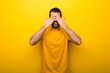Man on isolated vibrant yellow color covering eyes by hands. Surprised to see what is ahead