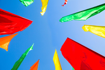 Decorative multicolored flags on blue sky background. Red, green, yellow flags. Street decorations