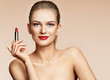 Woman applying red lipstick. Photo of attractive girl with perfect makeup on beige background. Beauty concept