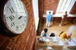 © pressmaster - Face of clock hanging on brick wall of modern office where group of casual employees working