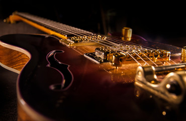 Closeup of sunburst electric guitar with brass mechanics and bright colors on a dark shaded background