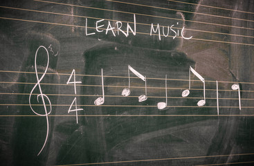 Random music notes written with white chalk on a blackboard. Learn or teach music concepts.