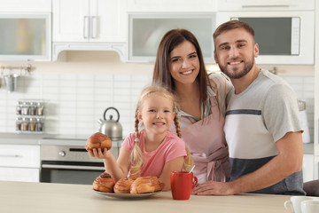 Canvas Print - Happy family with freshly oven baked buns at table in kitchen. Space for text