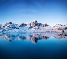 Aerial View At The Mountains And Reflection On The Water Surface. Lofoten Islands, Norway. Natural Landscape During Sunrise From Air. Drone Landscape
