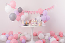 Party Treats And Items On Table In Room Decorated With Balloons