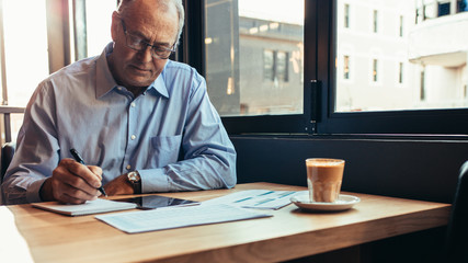 Wall Mural - Senior businessman working from a modern cafe