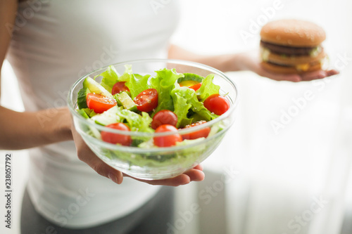 Fotomural Dieting concept, beautiful young woman choosing between healthy food and junk fo