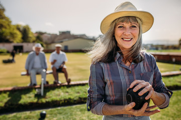 Wall Mural - Close up of a woman playing boules in a lawn