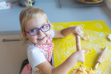 cute little girl with rolling pin preparing christmas cookies