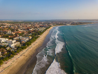 KUTA, BALI / INDONESIA - OCTOBER 25, 2018: Aerial view of Kuta town and beach with sun umbrellas lined up on the sand