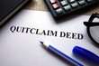 Quitclaim deed form, pen, glasses and calculator on desk