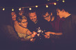© simona - Night party celebration like new year eve 2019 or chsristams for caucasian big modern family using sparkles light fireworks together in friendship having fun - people smiling and do party