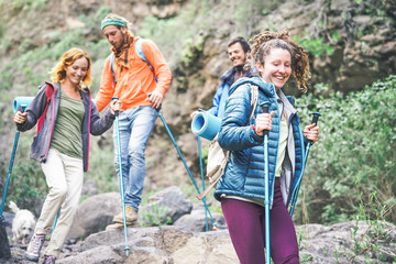 Group of friends with backpacks doing trekking excursion on mountain - Young  tourists walking and exploring the nature - Trekker, hike and travel people concept