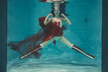 beautiful sexy girl swimming underwater in sporty style red and white fetish corset and over knee thigh high boots with heels