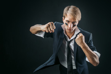 A young man in a business suit rolled up his sleeves and Boxing. Aggressive business, concept. Businessman