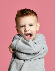 Wall Mural - Baby boy kid warlike angry shouting  screaming in gray hoodie over pink 