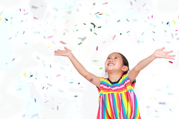 Happy little child girl with colorful confetti on white background. Happy New Year or Congratulation Concept.