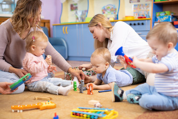 Friends with children toddlers playing on the floor in montessori centre