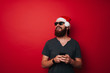 © Vulp - Happy bearded man with santa claus hat holding smartphone and looking away at copyspace