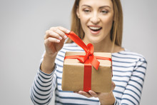 Smiling Woman Hold Gift Box Isolated Over White Background. Portrait Of A Joyful Young Woman Dressed In Casual, Holding Gift Box And Celebrating.