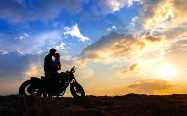 Wall Mural - Couple in love silhouettes with motorbike  at sunset sky