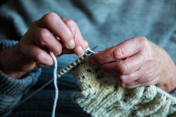 Close up of an older womens hands knitting a jumper