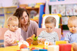 © Oksana Kuzmina - Children group playing with teacher in day care centre nursery playroom