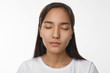 © shurkin_son - Peace, calmness, harmony and meditation concept. Beautiful young Asian woman with loose black hair having peaceful serene facial expression while meditating in studio, keeping her eyes closed