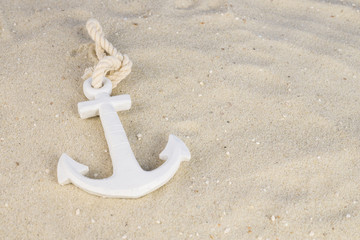 A white anchor in the sand on the beach