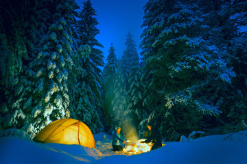 Wall Mural - couple camping with campfire and tent outdoors in winter