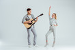 © LIGHTFIELD STUDIOS - handsome man playing acoustic guitar while woman dancing on grey background