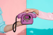 © LIGHTFIELD STUDIOS - cropped view of man and woman holding purple vintage telephone on pink and blue background