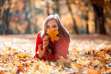 Natural Woman Holding Colorful Autumn Leaf Lying On Lawn In The Park