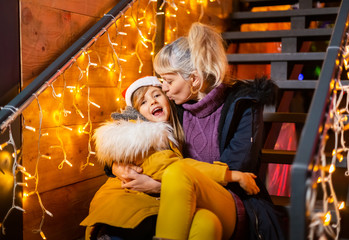 Wall Mural - Mother kissing cheek of daughter at Christmas market, Zagreb, Croatia.