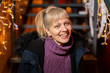 © paul prescott - Portrait of happy woman sitting on stairs at Christmas market.