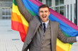 Happy businessman holding the rainbow flag