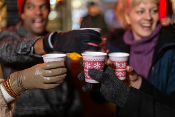 Wall Mural - Close up image of friends cheering with traditional drink at Christmas market.