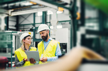 A portrait of an industrial man and woman engineer with tablet in a factory.