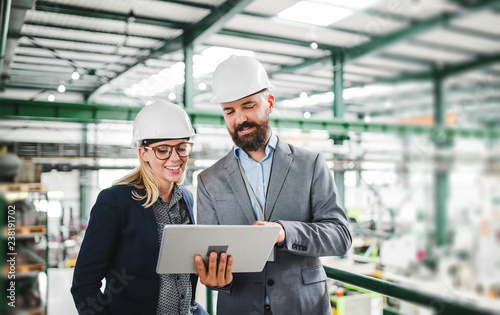 Cuadros en Lienzo A portrait of an industrial man and woman engineer with tablet in a factory, working