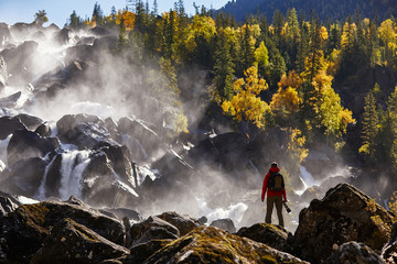 Photographer with backpack enjoying amazing waterfall Travel Lifestyle and success concept vacations into the wild nature