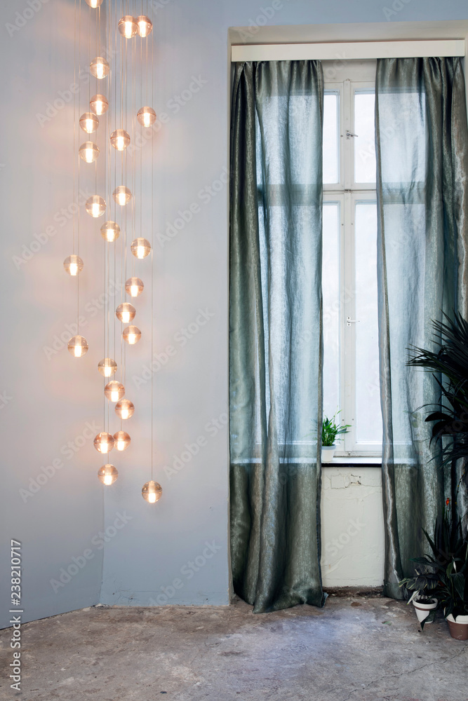 Stock-Foto „Grosse Hänge Lampe neben Fenster mit silbrig grünen transparent Vorhängen vor Fenster“