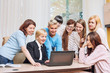 © kuzmichstudio - Group of women in the office at the seminar together discuss topics of interest at the table in front of a laptop