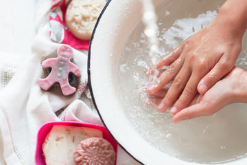 Child’s hands under white bowl with water upon water stream, colorful soaps on Child’s hands under white bowl with water upon water stream, colorful sa white material, cleanliness and hygiene concept 