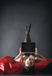 © Vitte Yevhen - Sexy young brunette woman in black sensual lingerie and in stockings using laptop on red bed in studio.