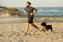 Happy Bearded Man Running Outdoor Near Sea With His Dog