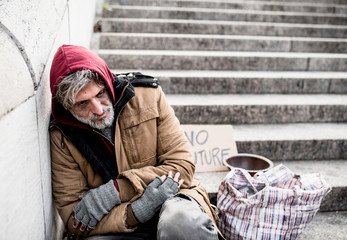 Wall Mural - Homeless beggar man sitting outdoors in city asking for money donation.