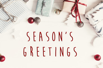 Wall Mural - Season's greetings text on modern christmas flat lay with ornaments and gift boxes, top view with space for text. Holiday  greeting card. Merry Christmas and Happy new year