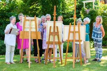 Senior women painting on canvas during sunny day.