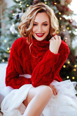 holidays, celebration and people concept - smiling woman in red sweater over christmas tree backgrou