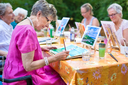 Fotomural Senior lady painting in art class with friends.